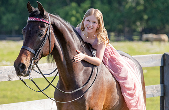 Portrait of Claire New in a pink dress on her Morgan horse, Riley.